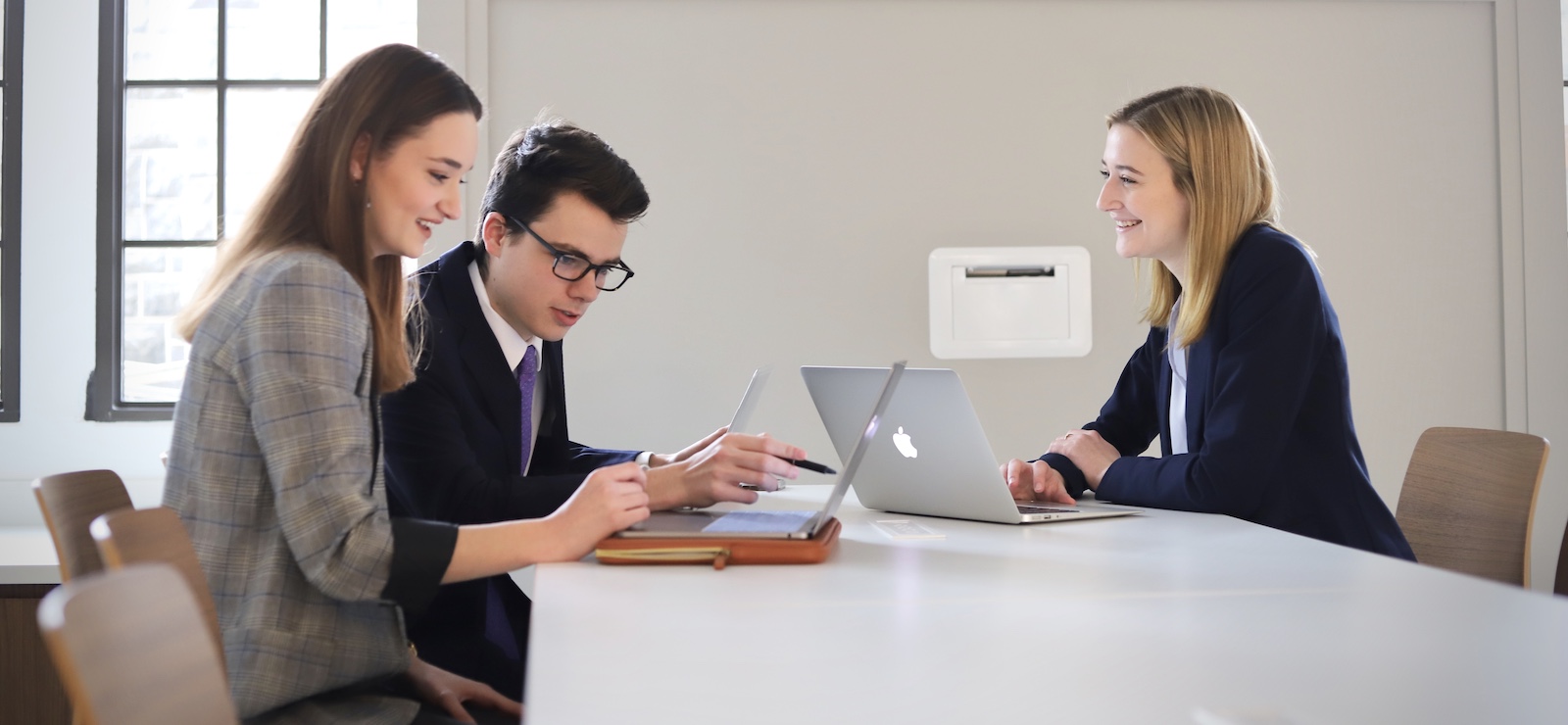 students dressed professionally collaborate on a project in the business school