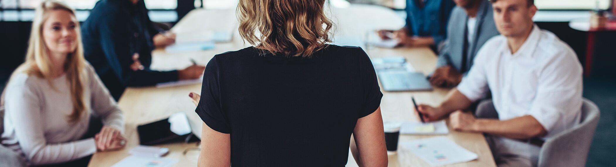 Photo of a woman presenting to a boardroom.