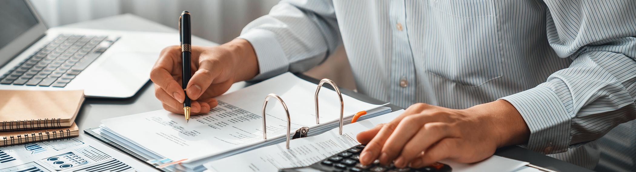 Photo of a man at a ledger with a calculator. 