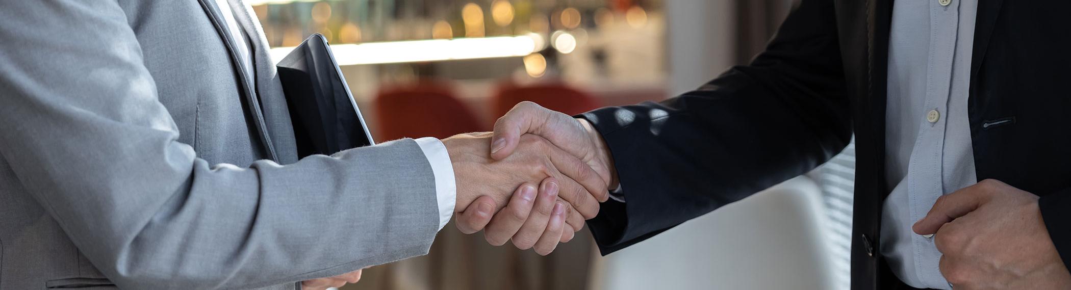 Two business professionals shaking hands during a sales deal.