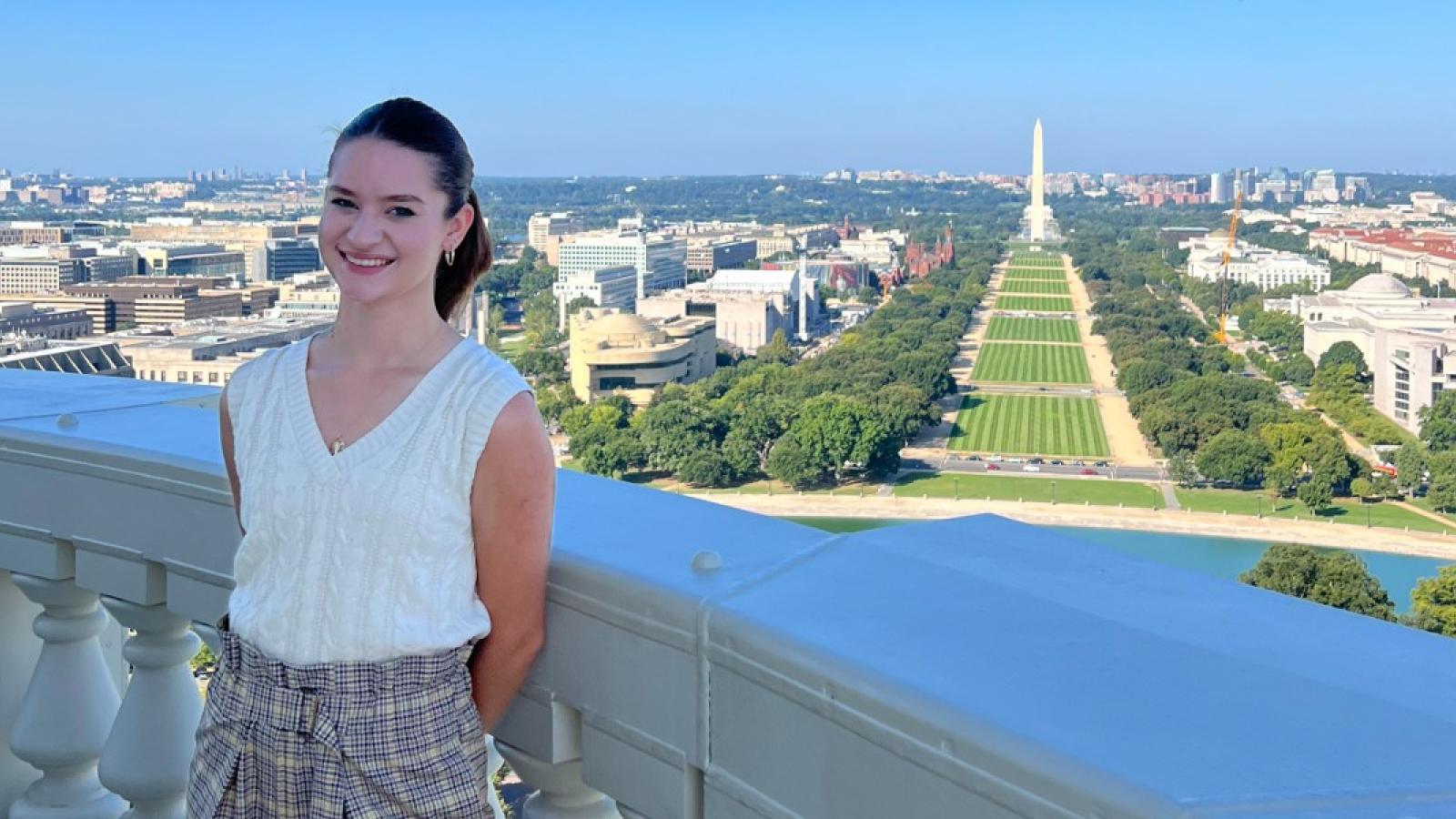 julia on a balcony at the capitol building with the washington monument and national mall in the background