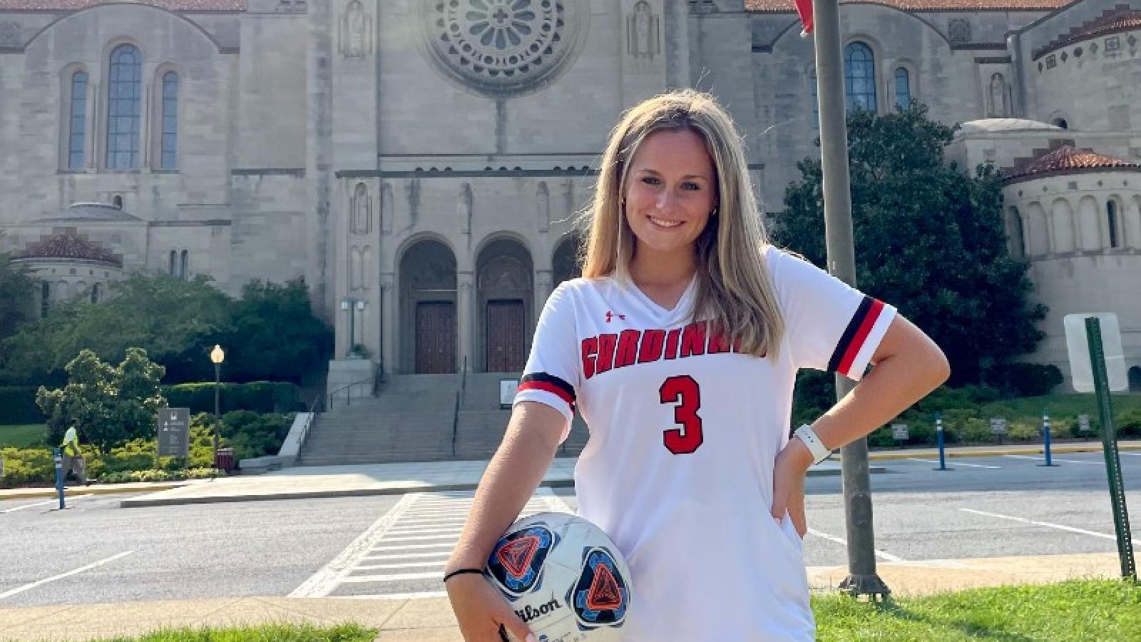 emily in her soccer uniform posing in front of the basilica of the national shrine of the immaculate conception