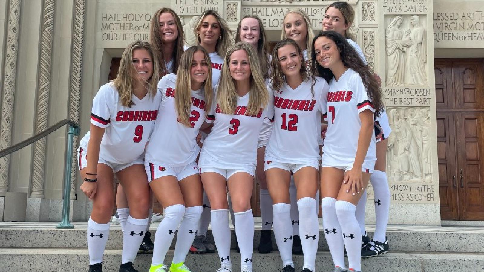 emily and the CUA soccer team pose on the steps of the basilica