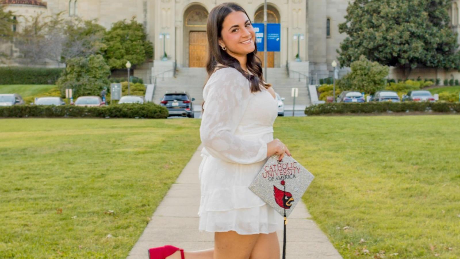 isabella with her graduation cap posing on campus
