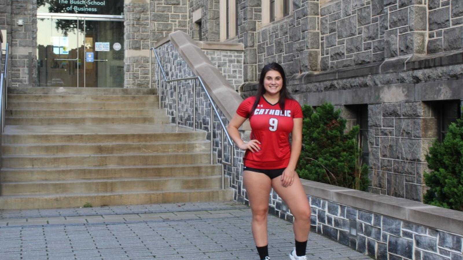 katie in her CUA volleyball uniform in front of the business school