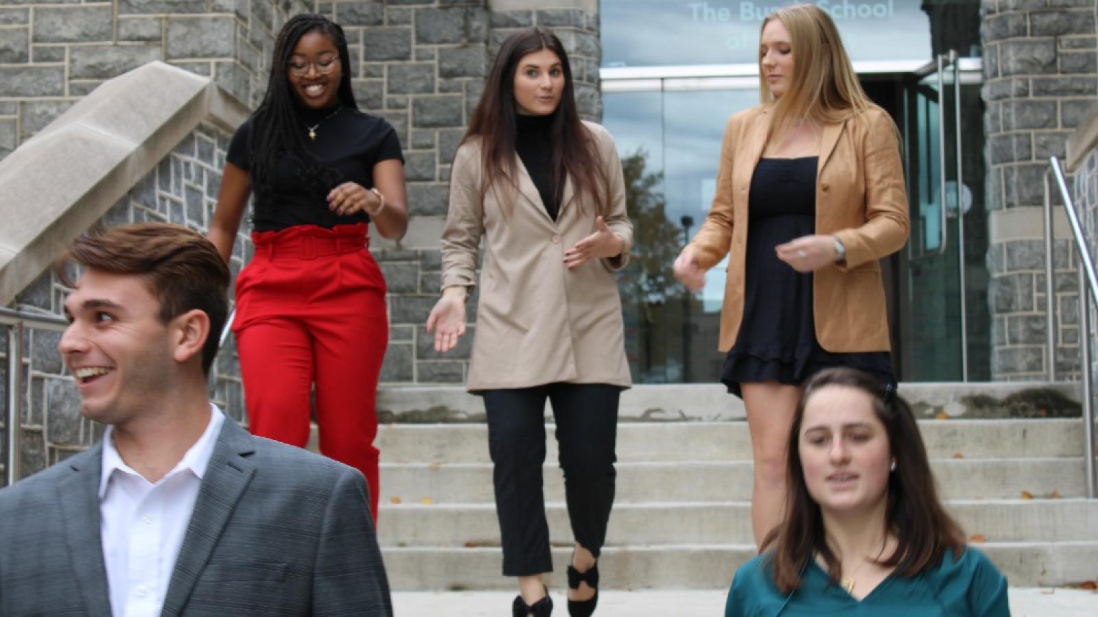 stephanie and her classmates walking down the front steps of maloney hall dressed in business attire