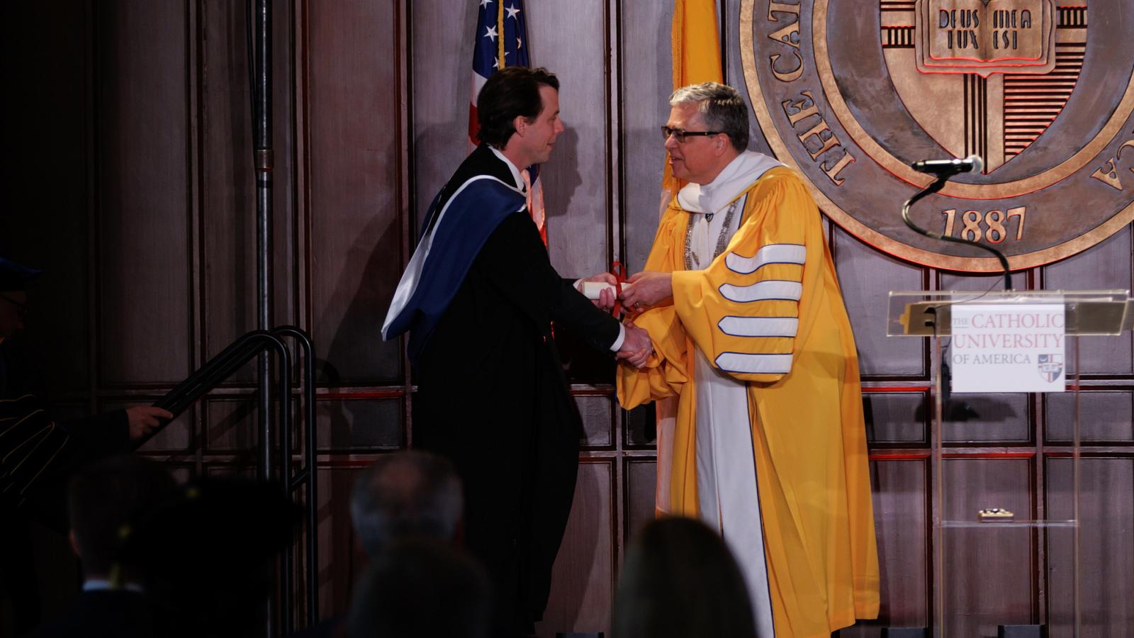 Professor Nicholas Schmitz shakes President Kilpatrick's hand at the chair inauguration ceremony