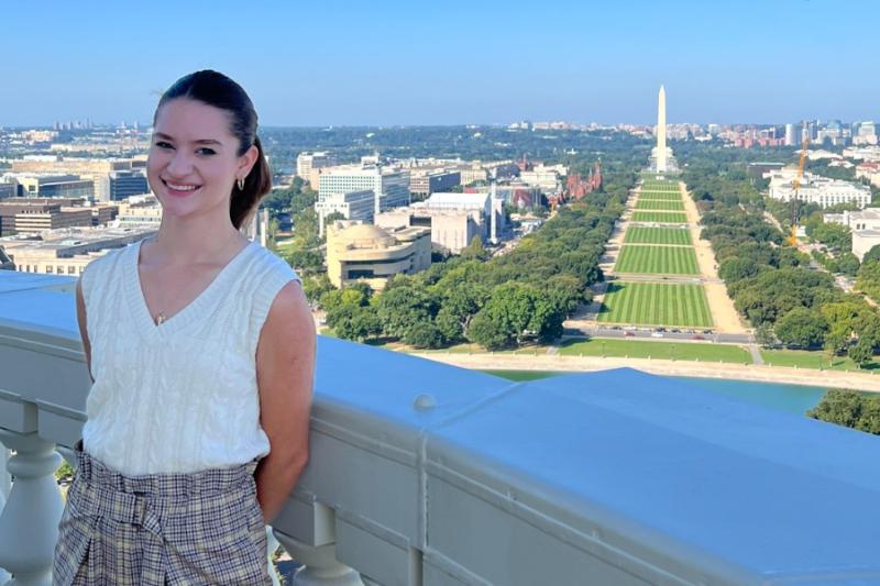 julia on a balcony at the capitol building with the washington monument and national mall in the background