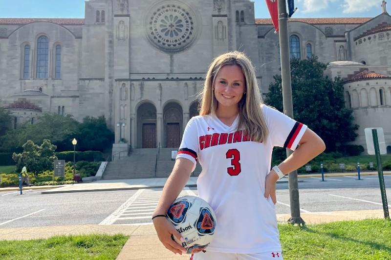 emily in her soccer uniform posing in front of the basilica of the national shrine of the immaculate conception