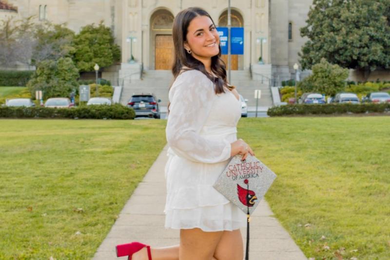 isabella with her graduation cap posing on campus