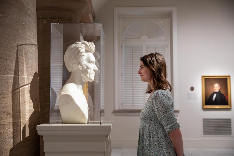 young woman staring eye to eye of a statue of Lincoln in a museum