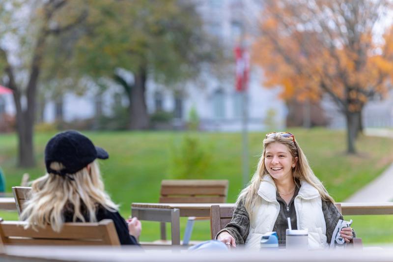 Students talking at a table on the lawn.
