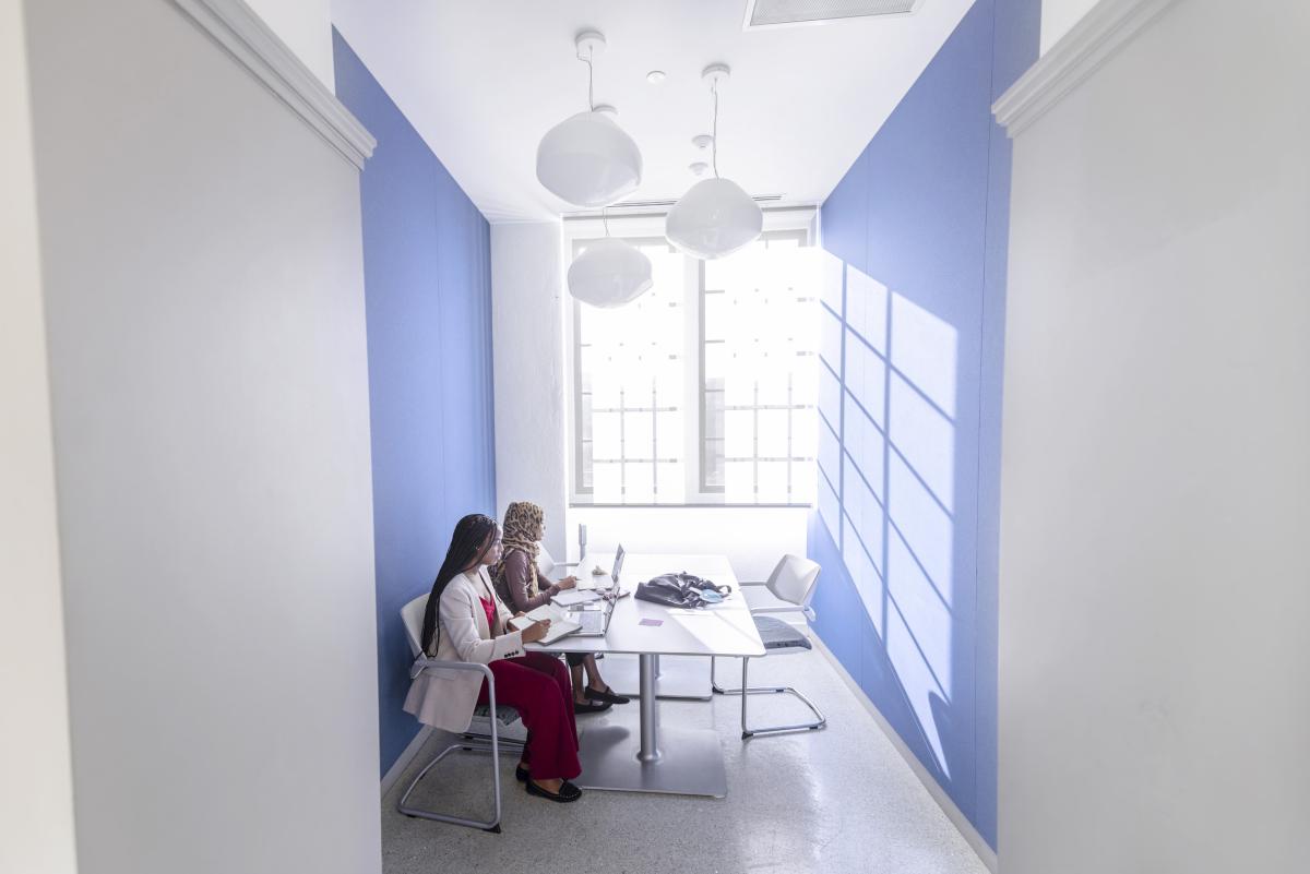 two female students in a study room with a bright sun shining through a large two-panel windowwindow