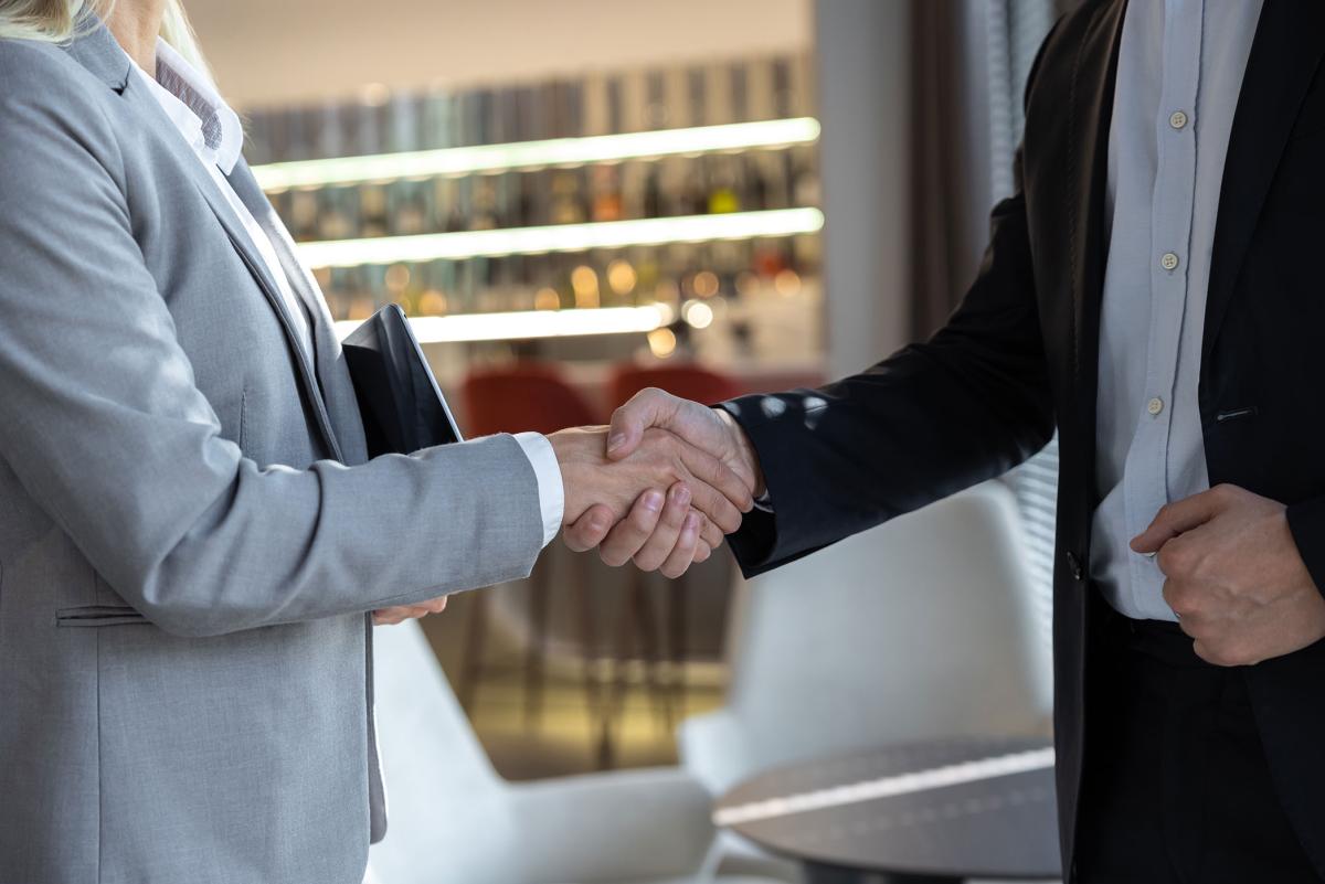 Two business professionals shaking hands during a sales deal.