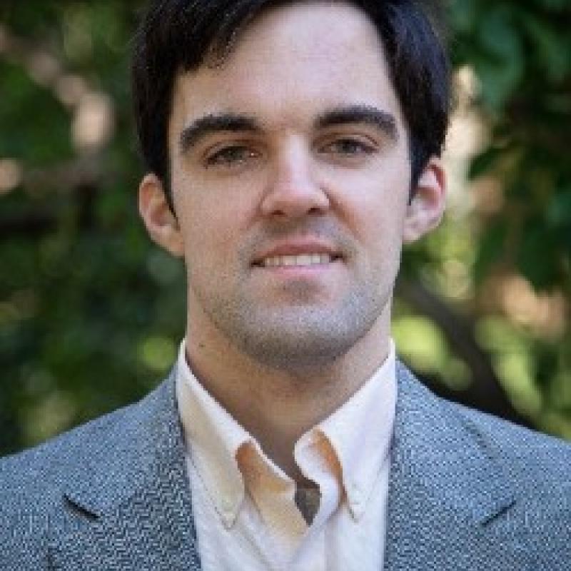 Photo of Daniel Svogun. He has short dark hair. He is wearing a grey suit with a pink shirt.