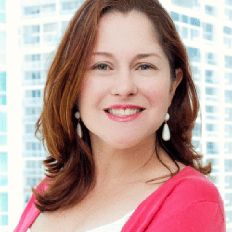 Photo of Ana Gamonal. She has shoulder-lenght brown hair, is wearing a pink cardigan over a white shirt, and has droop pearl earrings.