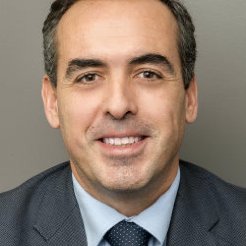 Photo of Francisco Lara. He is wearing a grey suit, a blue shirt, and a navy tie.