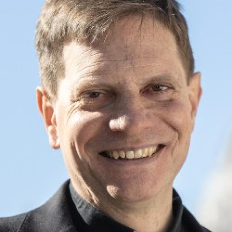 Photo of Robert Gahl. He has short brown hair and is wearing a black shirt and a clerical collar.