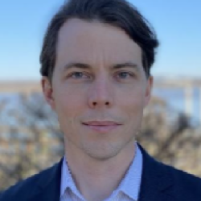 Photo of Nicholas Schmitz. He has short brown hair and is wearing a navy suit over a white shirt.