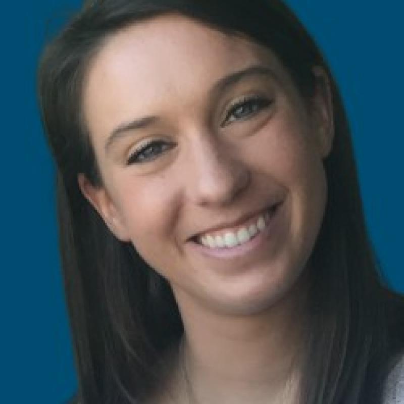 Photo of Molly McManamon. She has long dark brown hair, and is wearing a cream sweater.