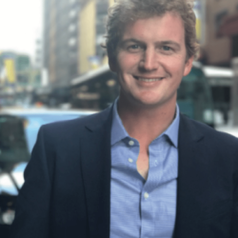 Photo of Patrick Langrell. He has curly blonde hair. He is wearing a navy blazer and a blue shirt.