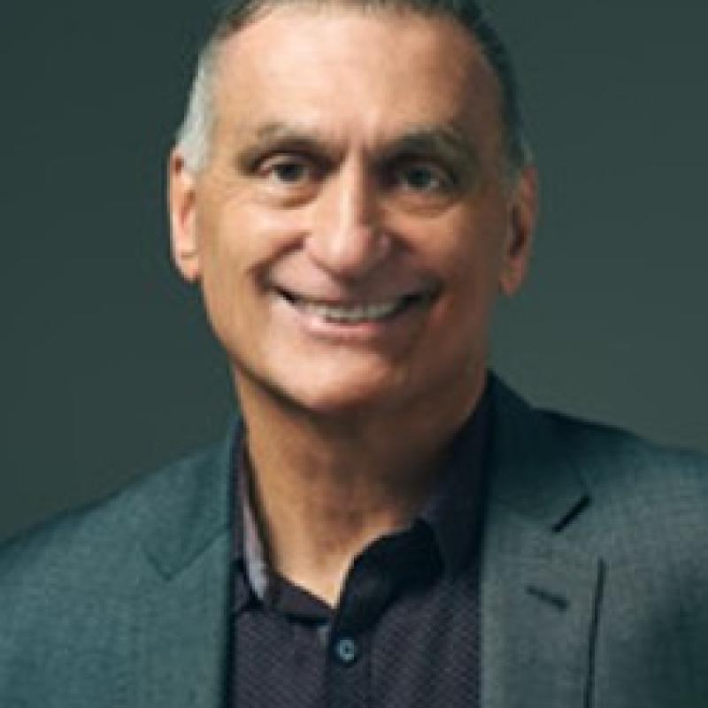 Photo of Deacon Rich Napoli. He has short salt-and-pepper hair. He is wearing a grey suit and a black shirt.