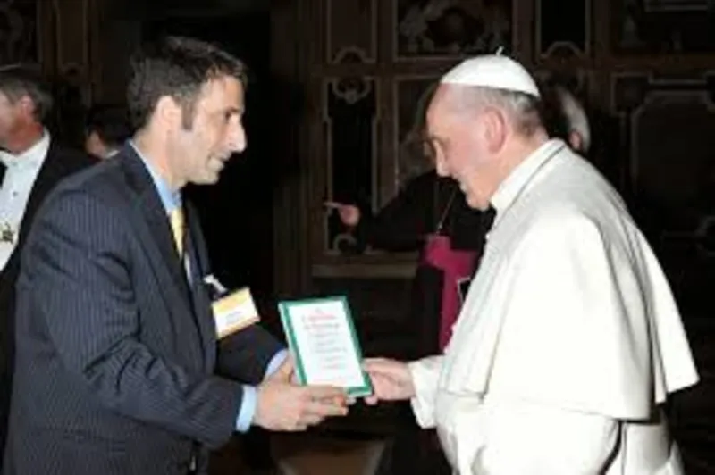 Abela meeting Pope Francis and handing him a copy of his book
