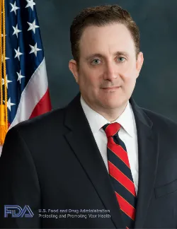 Photo of David Gortler. He has short brown hair and is wearing a black suit with a blue and white tie.