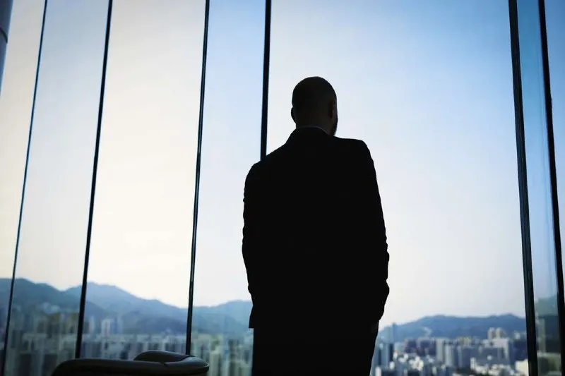 businessman looking out the window on a high floor of a building