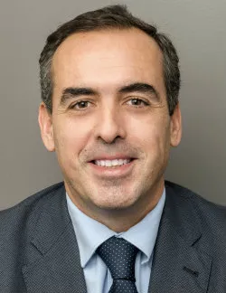 Photo of Francisco Lara. He is wearing a grey suit, a blue shirt, and a navy tie.