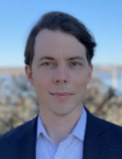 Photo of Nicholas Schmitz. He has short brown hair and is wearing a navy suit over a white shirt.