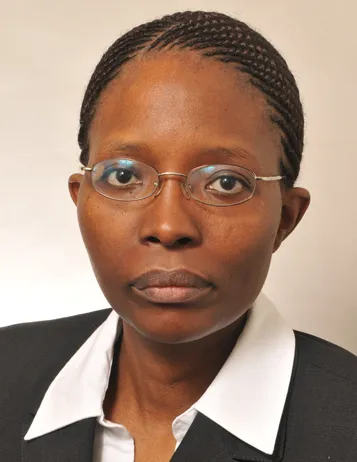 Photo of Mary M Njeri Njai. She is wearing a black suit with a white shirt and is wearing thin glasses.