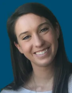 Photo of Molly McManamon. She has long dark brown hair, and is wearing a cream sweater.