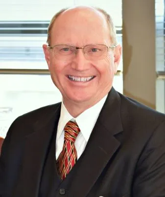 Photo of J Patrick Kearns. He is wearing a black suit and a red, green, and blue tie.