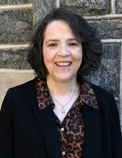 Photo of Rebecca Ryskind Teti. She has bobbed dark hair. She is wearing a black cardigan over an animal print button down shirt.