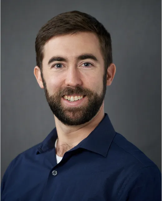 Photo of Richard Gallenstein. He is wearing a navy blue button down shirt and has a brown beard.