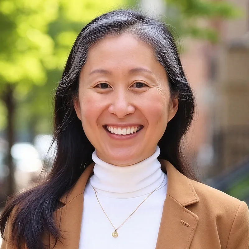 Photo of Cabrini Pak. She has long black hair and is wearing a tan professional jacket.